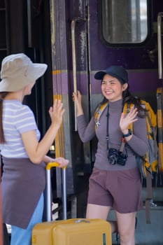 two young asian friends girls with backpacks at railway station waiting for train, Two beautiful women walking along platform at train station photo