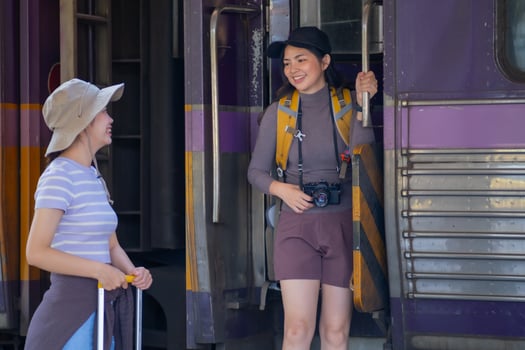 two young asian friends girls with backpacks at railway station waiting for train, Two beautiful women walking along platform at train station photo