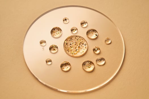 Serum with 24K Gold particles. Drops on a beige background. photo