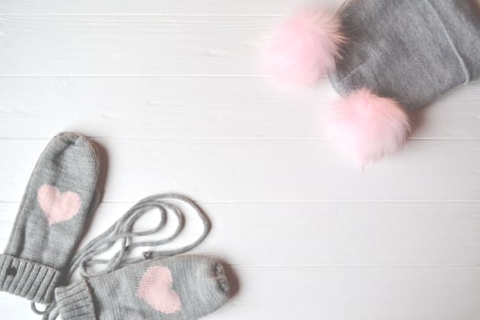 Hat and mittens on the white desk. Knitted winter clothes. Stylish background with place for text. photo