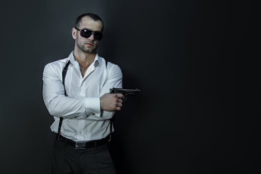 Young man in glasses wears holds a gun in his hand photo
