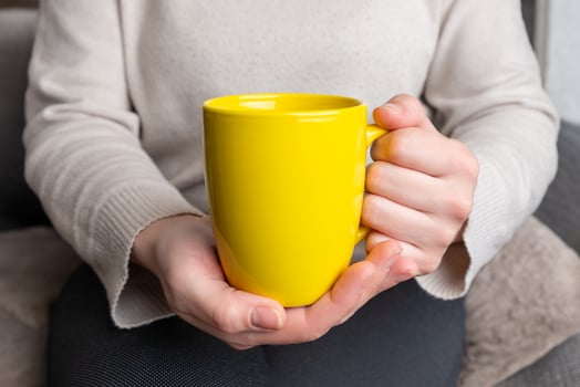 Woman's hands hold a yellow clean mug, providing a flawless surface for promoting custom mug designs photo