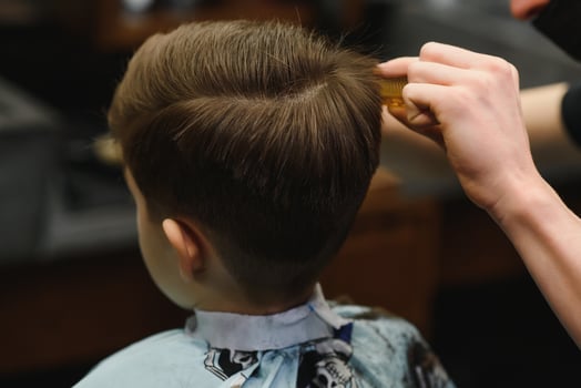 Cheerful Caucasian boy getting hairstyle in barbershop photo