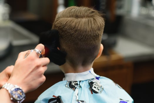 A little cute boy sits in a hairdresser's at the stylist's, a schoolchild is getting hair cut in a beauty salon, a child at a barbershop's, a short men's haircut photo