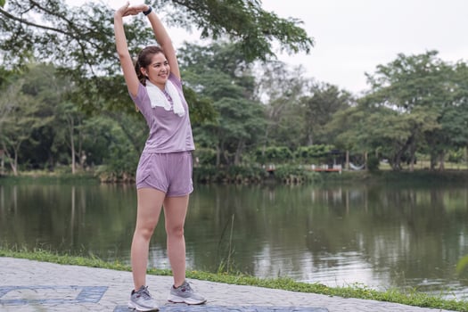 Young Asian woman takes care of her health by exercising. Stretch your legs in the park photo