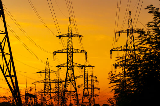 Electricity pylons bearing the power supply across a rural landscape. Selective focus. Beautiful sunset agains metal pylons. photo