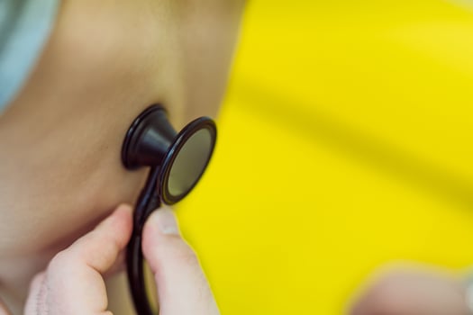 Male doctor using stethoscope to examining little boy. Selective focus. Closeup. photo