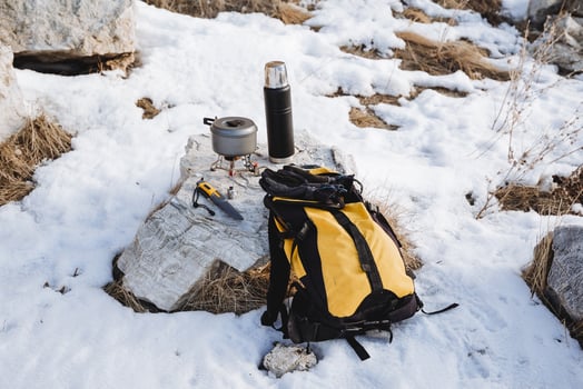 Hiking equipment hiking in winter mountainous terrain yellow backpack thermos hot coffee pot stands on burner gas knife survivalist equipment tourist photo
