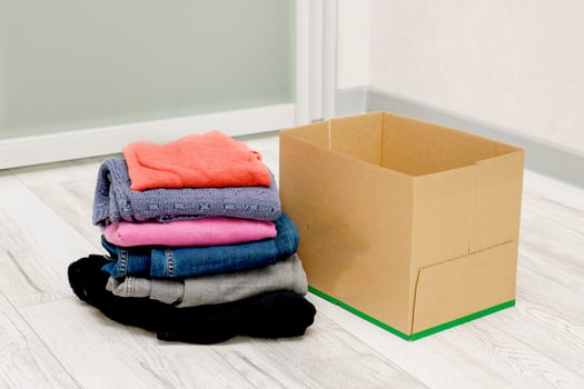 folded clothes next to an empty box on the floor photo