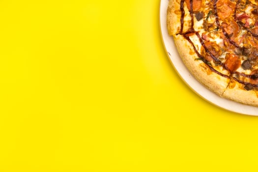 Delicious large pizza with bacon and spinach on a yellow background photo