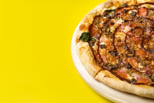 Delicious large pizza with bacon and spinach on a yellow background photo