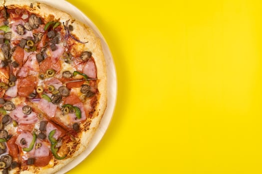 Delicious large pizza with veal and mushrooms on a yellow background photo