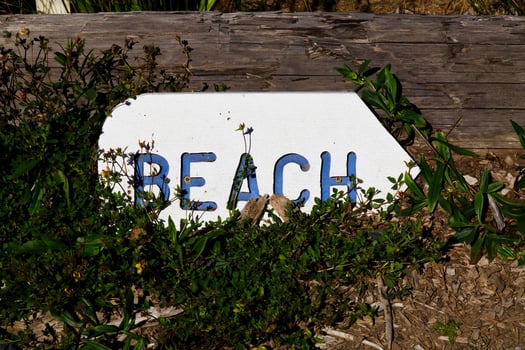 Wooden Sign Pointing To Beach Blue Letters White Background photo