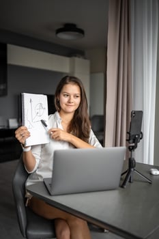 A young woman blogger conducts an educational broadcast on a laptop in social network in home workplace, online teaching concept photo