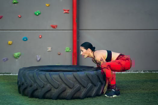 Sportive woman lifting a truck wheel in a gym photo