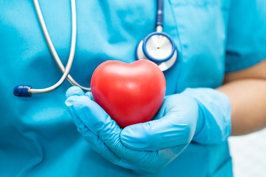 Doctor holding a red heart in hospital ward, healthy strong medical concept. photo