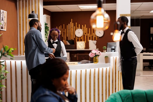 Friendly welcoming female receptionist helping tourist with check-in procedure at front desk. African American hotel staff assisting guest at reception, customer service in hospitality industry photo