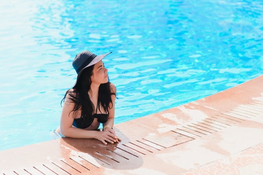 Vacation lifestyle scene of young woman sitting in swimming pool in morning time. Weekend and holiday lifestyle concept photo