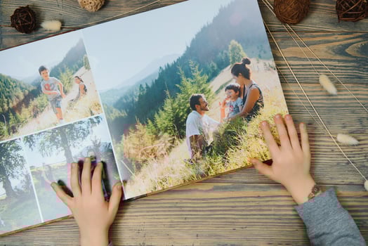 the Hand child holding a family photo album against the background of the a wooden table