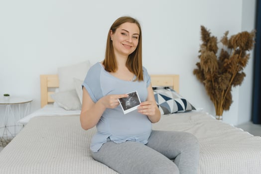 pregnant woman holding ultrasound scan on her belly photo