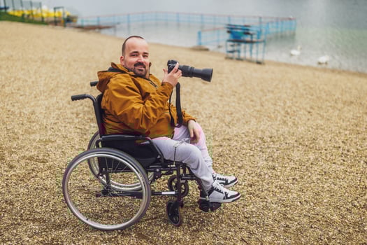 Paraplegic handicapped man in wheelchair is photographing outdoor. photo