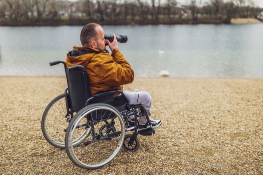 Paraplegic handicapped man in wheelchair is photographing outdoor. photo