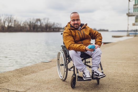 Happy paraplegic handicapped man in wheelchair by the lake. He is ready for exercise with weights. photo