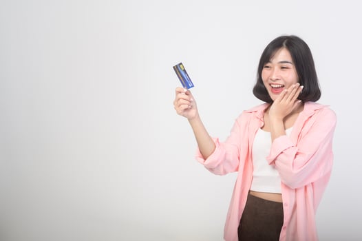 Asian smiling woman holding credit card over white background studio, shopping and finance concept. photo