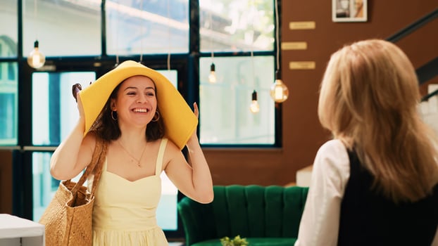 Female client approaching reception in hotel lobby, asking front desk staff about room reservation for tropical holiday during summertime. Woman entering lounge area with trolley bags. photo