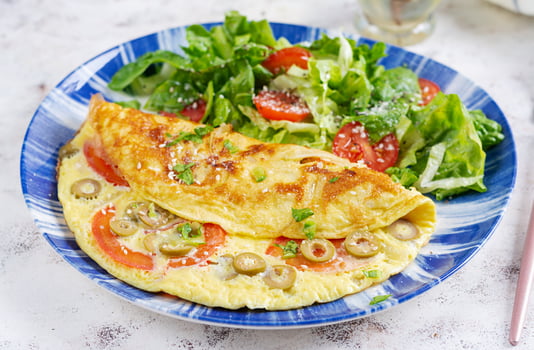 Omelette with tomatoes, green olives and fresh salad on blue plate.  Frittata - italian omelet. photo
