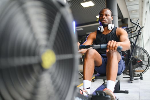 Motivated young black sportsman having workout on rowing machine photo
