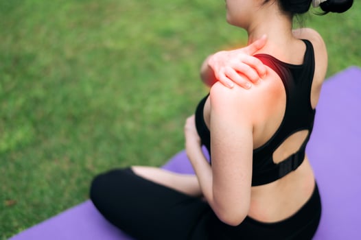 Woman jogger. young 30s asian female wearing black sportswear holding her shoulder pain after exercise in public park. Pain in activity concept. photo