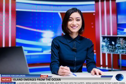Asian reporter presents new island appearance on television show, rare natural events occured on ocean shoreline. Woman presenter talks about new exploration region for nature lovers. photo