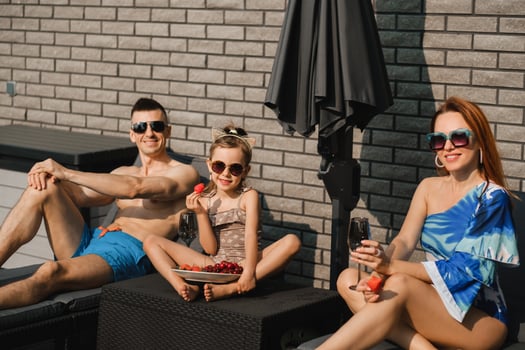 A happy family in swimsuits sunbathe in summer on their terrace on sun beds photo