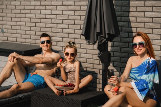 A happy family in swimsuits sunbathe in summer on their terrace on sun beds photo