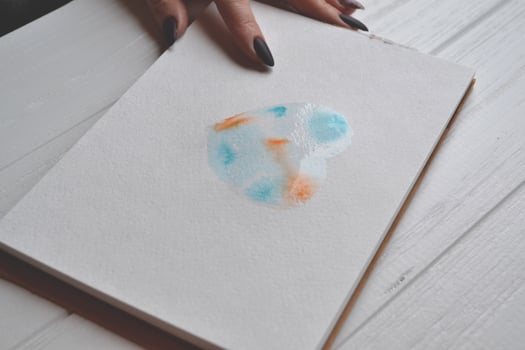 Woman paints in a sketchbook. Tools for painting on the white wooden desk. Painter work. photo