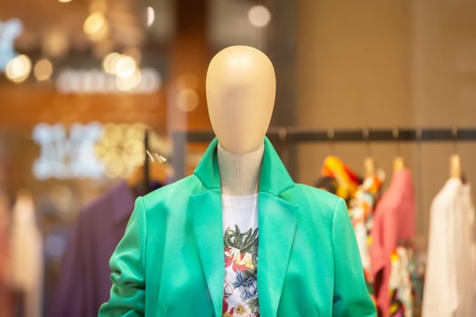 A female mannequin in a green jacket behind the glass of a store window. photo