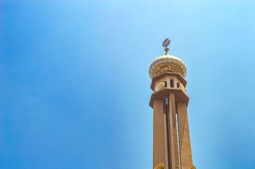 a mosque minaret against a bright blue sky background photo