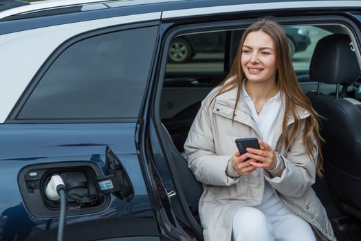 Young woman charging her electric car at a charging station in the city. Eco fuel concept. The concept of environmentally friendly transport. Recharging battery from charging station. photo