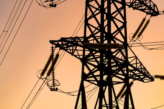 Energy transmission towers or electricity pylons with golden sky and clouds. Selective focus. Cropped photo from below.