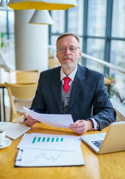 Successful man with laptop in modern white office with glass big windows around. Male in suit photo