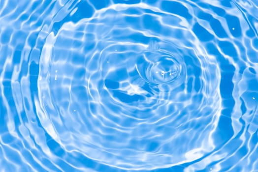 Bluewater waves on the surface ripples blurred. Defocus blurred transparent blue colored clear calm water surface texture with splash and bubbles. Water waves with shining pattern texture background. photo