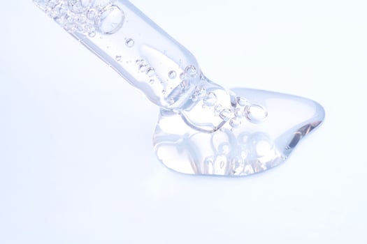 Pipette with sample of gels cosmetic product in petri dish on blue background, hard shadows, selective focus photo