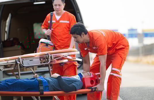 The paramedic  is assisting an injured man in an emergency situation on the road. photo