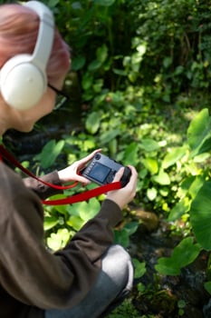 Beautiful Young artist Woman taking photo in flowers garden. Young cute girl carry the camera in the garden