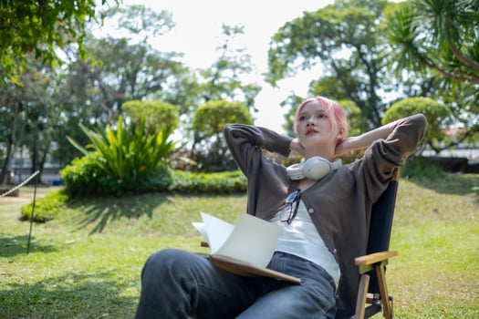Young Happy Asian artist woman drawing book and wearing headphone, the artist paints in the garden photo