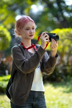 Beautiful Young artist Woman taking photo in flowers garden. Young cute girl carry the camera in the garden