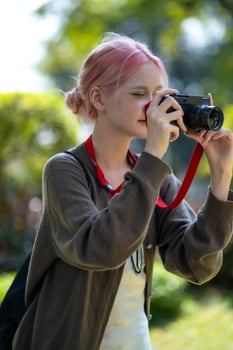 Beautiful Young artist Woman taking photo in flowers garden. Young cute girl carry the camera in the garden
