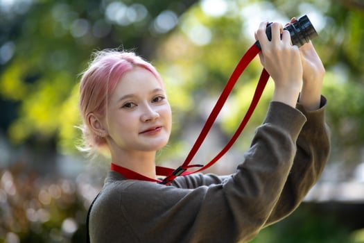 Beautiful Young artist Woman taking photo in flowers garden. Young cute girl carry the camera in the garden