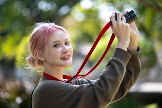 Beautiful Young artist Woman taking photo in flowers garden. Young cute girl carry the camera in the garden